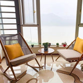 鋁合金時尚搖椅配米色坐墊與黃色靠枕,窗邊休閒角落欣賞湖景山色 | Aluminum alloy rocking chairs with beige cushions and yellow pillows, window relaxation corner with lake and mountain view