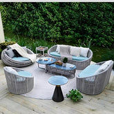 北歐風格灰色藤編戶外休閑沙發,搭配淺藍色座墊和米色靠枕,圓弧形鋁合金框架設計,適合露台花園使用的防水防曬時尚傢俬。Nordic style gray rattan outdoor leisure sofa with light blue cushions and beige pillows, curved aluminum frame design, waterproof furniture ideal for terrace and garden use.